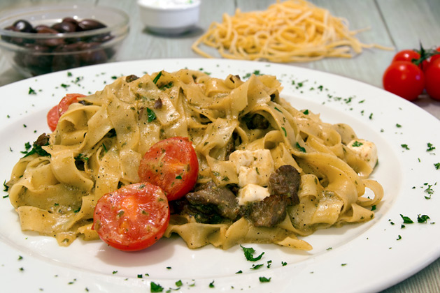 Taliateles with pieces of beef, pesto sauce, baby tomatoes and feta cheese